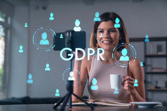 Happy woman is making video blog using smartphone on a tripod explaining with hands at office workplace. Concept of online stream, business education, conference call. Information security hologram