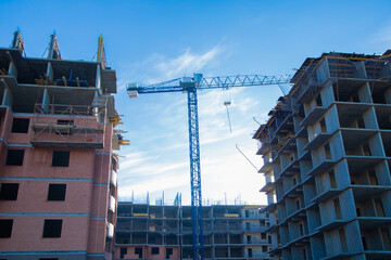 The construction of two large buildings, surrounded by cranes and scaffolding, against a clear blue sky, demonstrates the development of the city and architectural progress. The concept of © Ксения Мнасина