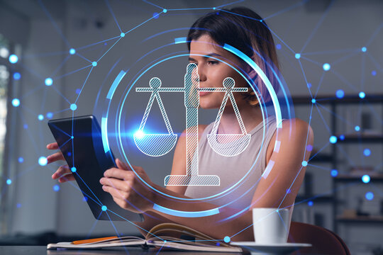 Smiling businesswoman in casual wear holding tablet device touching it at office workplace. Concept of distant work, business education, information technology. Law and order icons hologram