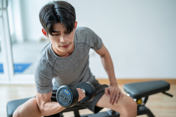 Asian young sportsman exercising to building muscle in gym stadium.