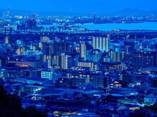 夜明け前の神戸市街地と大阪湾を隔てた大阪の市街地