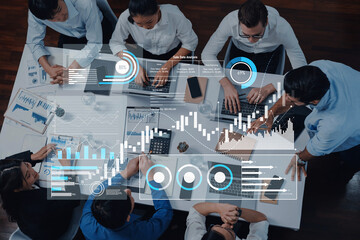 A diverse business team collaborates in a modern office setting, analyzing data on laptops, surrounded by graphical visuals and charts for effective decision-making. Trope