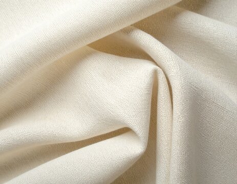 Close-up view of a light-colored, textured fabric with folds and shadows