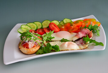 Spiegelei mit Baconm frische Gemüsen und Bruschetta auf dem weißen Teller