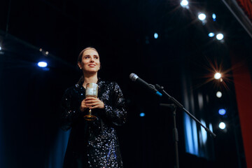 Woman Holding a Champaign Glass Making a Toast on Stage. Happy entertainer toasting for the New Year public celebration
