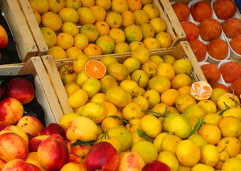 crates of fruit for sale at the produce vendors market stall featuring citrus and fresh peaches
