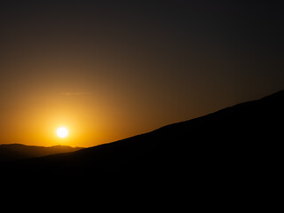 高原から望むオレンジ色に染まる夕日と雄大な自然の美しい風景