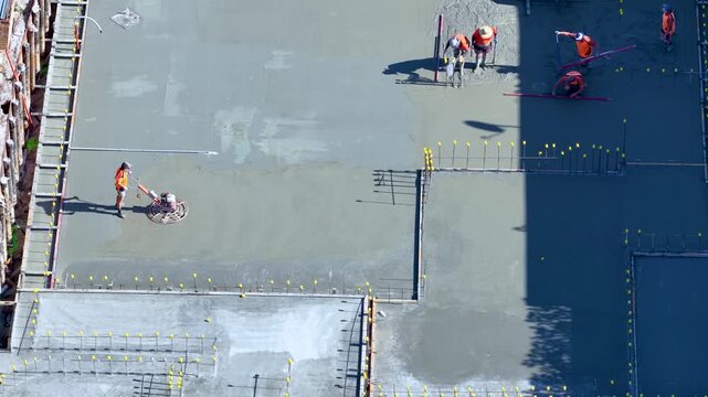Construction Workers Smoothing Wet Concrete on Building Site