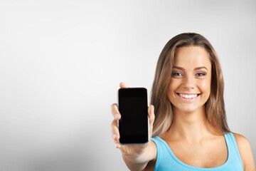 Fototapeta premium Smiling young woman hold mobile phone with blank screen