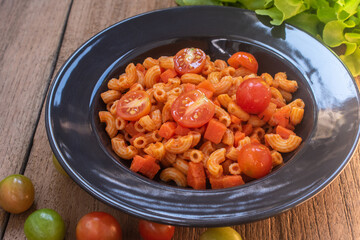 Classic macaroni and tomato sauce on a black plate.