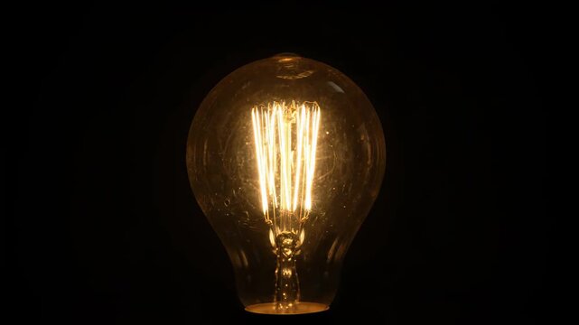 Vintage light bulb on black background shows retro idea this is a very warm and glowing filament lamp this is a very beautiful and simple energy concept this is a great design element