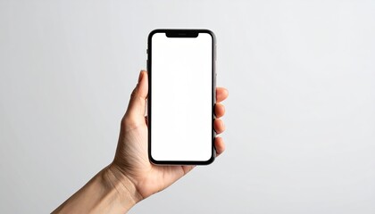 Hand holding a modern smartphone with a blank white screen in a studio setting with soft lighting
