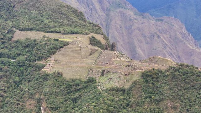 A complex shot performs a close-up circle around entire Machu Picchu citadel while simultaneously rising vertically. Camera pans down during ascent to achieve a stunning top-down view of ancient city
