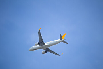Passenger airplane isolated on blue sky background. A yellow tailed passenger plane is flying. Aviation idea concept. Air transportation. Copy space, blank. 