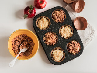 Making muffins with apples and cinnamon crumble on a light background, top view
