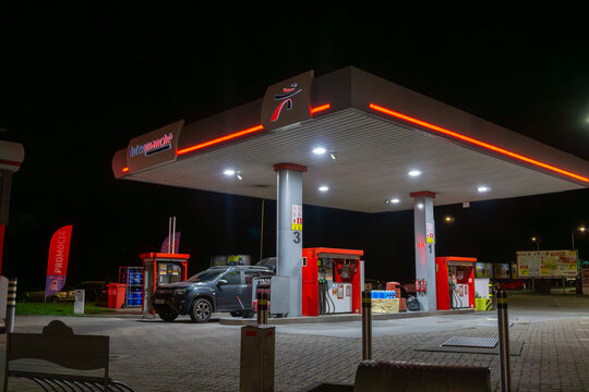 Intermarch&eacute; gas station at night with illuminated roof, fuel pumps and parked car at refueling position