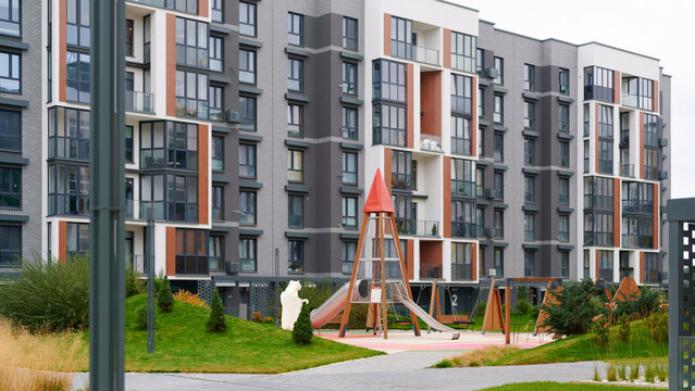 modern residential complex with playground surrounded by lush green landscaping. stylish architecture of high-rise apartments combined with communal outdoor area offers family-friendly environment