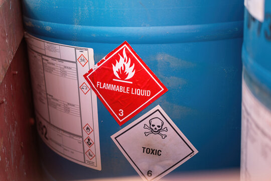 Flammable liquid warning sign on the chemical containment gallon. Industrial safety sign on the object, close-up with selective focus.