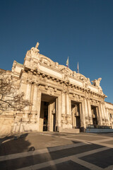 Obraz premium Milano Centrale Railway Station — Monumental Façade with Winged Horses and Bikes Afternoon light on the monumental limestone façade of Stazione di Milano Centrale (Milan Central Station), with massive