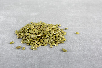 Hulled pumpkin seeds on gray background, side view