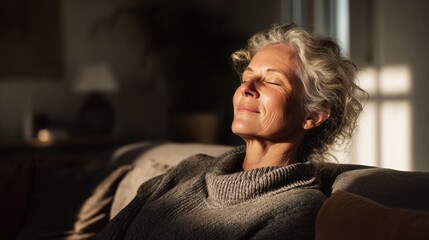 Woman enjoying sunlight indoors with eyes closed sitting on a sofa