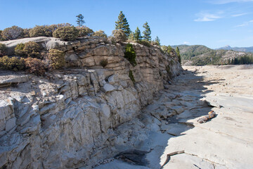 Dry rocky canyon landscape with cliffside trees and clear blue sky