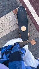 Skateboarder on city sidewalk, wearing sneakers and casual outfit