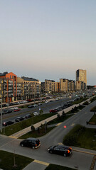 Obraz premium Cityscape at dusk with modern buildings and cars in the street