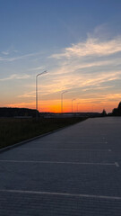 Sunset over an empty parking lot with street lamps