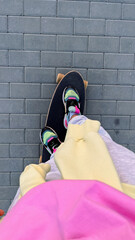 Skateboarder on city sidewalk, wearing sneakers and casual outfit
