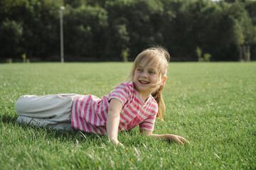 Little girl laying down in the green grass in the park