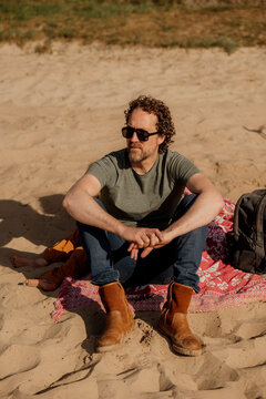 Man sitting on blanket at sunny sandy beach