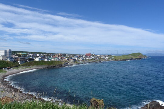 Coastal town on Rishiri Island, Hokkaido, Japan, along a rocky bay and the blue Sea of Japan under a wide summer sky