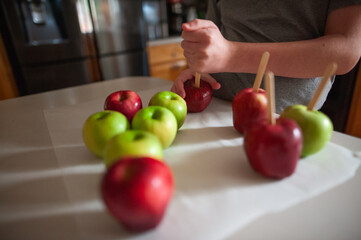 Teen placing sticks in apples for dipping at home