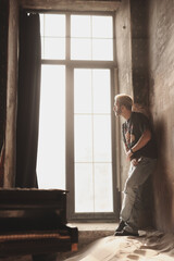 Man standing by a large window in an old building during daylight