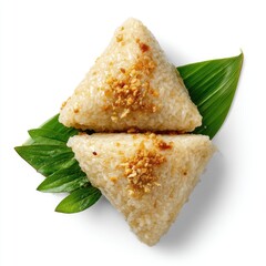 Two triangular rice cakes, topped with toasted nuts, rest atop a bed of vibrant green leaves