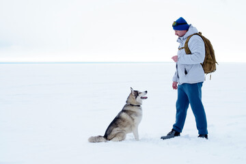 Caucasian man and Siberian husky on winter walk. the owner and the pet spend time together.