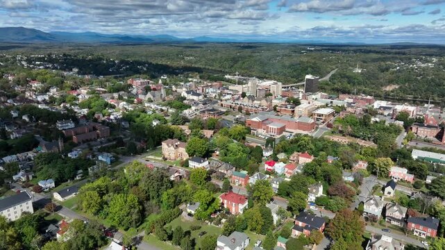Establishing drone shot of Lynchburg city in Virginia during sunny autumnal day. Colored trees, row of houses and downtown buildings. Wide shot. Peaceful serene atmosphere in autumn season.