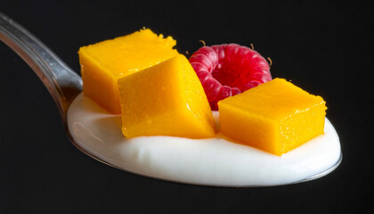Yogurt with diced mango and raspberry halves on porcelain spoon, macro
