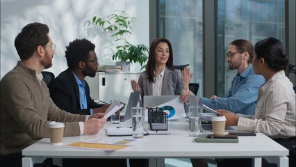 Multicultural Caucasian Indian group businesswomen businessmen women men business teamwork office coworkers females males discuss project together talking paperwork documents cooperate diverse people