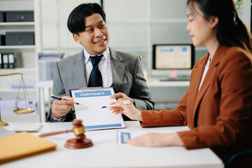 Two professionals discussing legal documents with justice scales on desk in modern office, symbolizing law, consulting