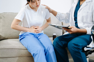 Obraz premium Doctor giving medication to patient suffering from stomach pain, showing healthcare, diagnosis, and medical treatment in a clinical consultation setting.