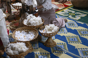 Traditional Asian ceremony showcasing solemn custom. Woven baskets filled with cotton offerings sit on decorative patterned mat during this cultural ritual celebration