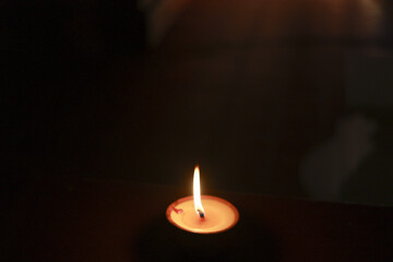 Single burning candle light creates peaceful, warm flame in dark. spiritual symbol of hope and fire glowing against black background offering serene contemplation