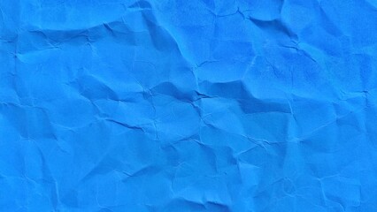 Wrinkled blue paper background with soft wavy texture. Background of a crumpled and folded blue paper. Wrinkled paper background with copy space for text.