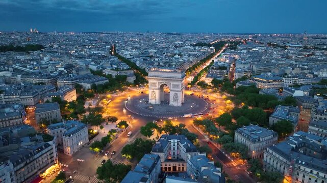Aerial night view of the famous landmark Triumphal Arch or Arc de Triomphe and Eiffel Tower surrounded by busy streets and lush greenery in the heart of the city Paris, France. Drone orbiting flight