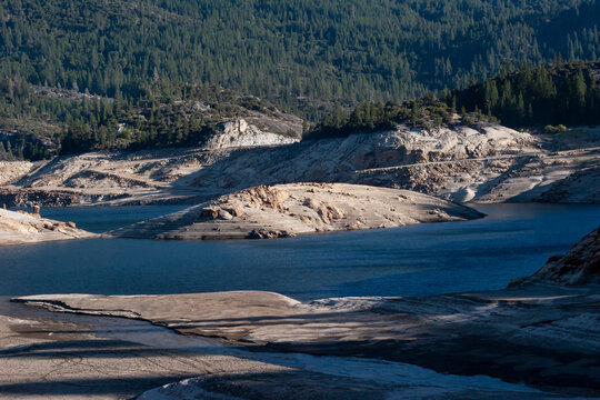 Low water levels reveal rocky terrain in mountain reservoir
