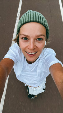 Young woman  rides a skateboard wearing green beanie on urban street