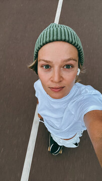 Young woman  rides a skateboard wearing green beanie on urban street