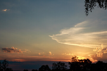 Glorious summer sunset bathes the vast sky in warm golden light. Sunbeams pierce through dynamic clouds, creating a peaceful, vivid natural landscape